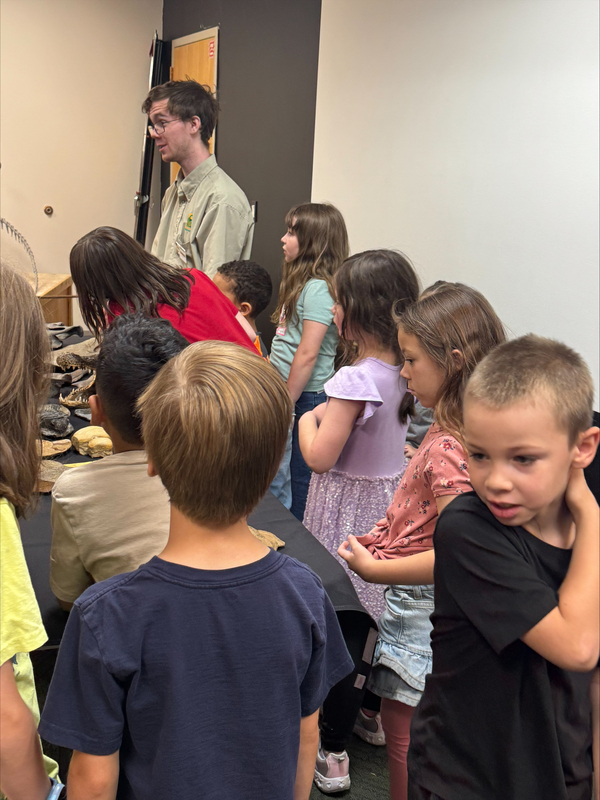 Students gather around a table during a fossil presentation.