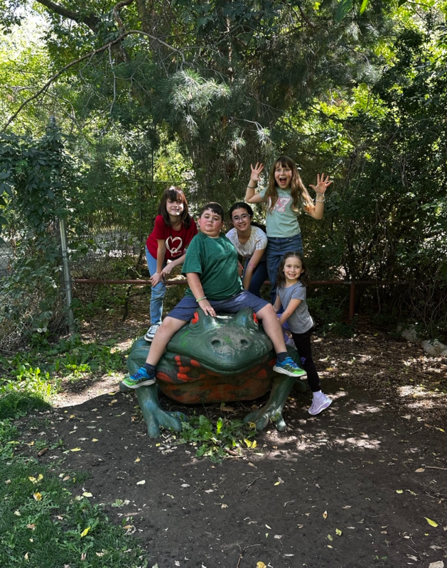 Five students pose around a giant toad sculpture.