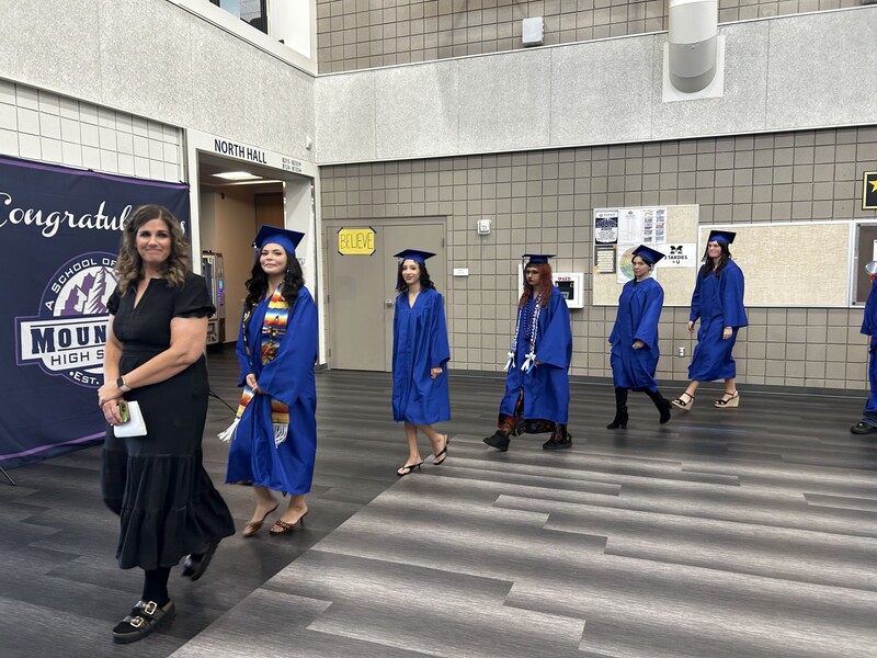 Graduation procession lead by Administrator Intern Lyndsi Drysdale. Students following her in blue cap and gowns