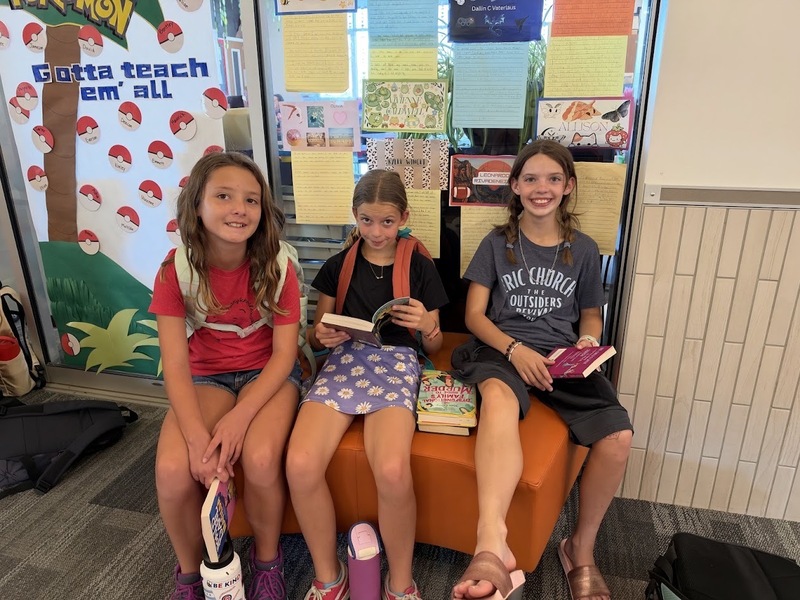3 student posing for a picture reading their books.