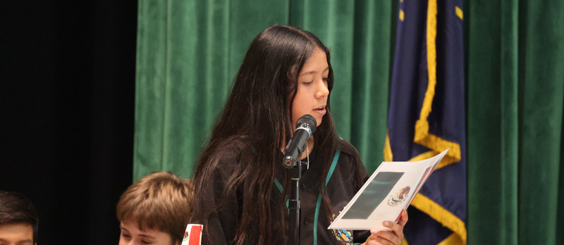 A Foxboro Elementary student reading about her heritage into a microphone.