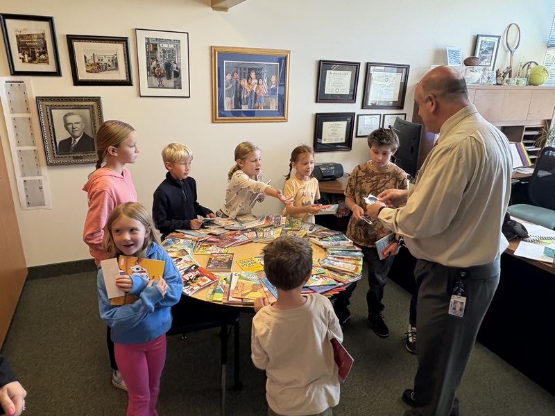 Students from the 100s club receiving a book and other prizes from the principal. 