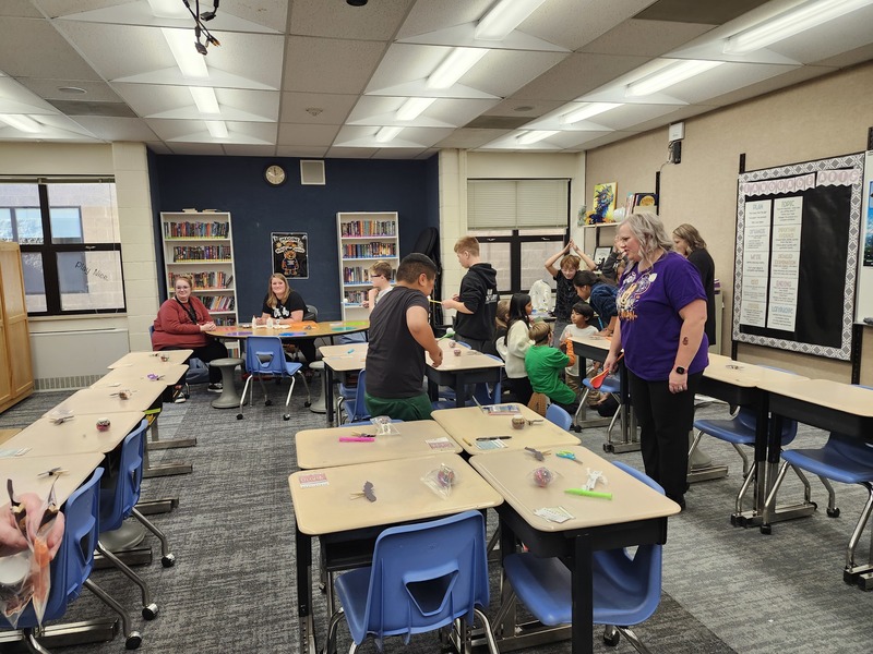 Parent volunteers helping students play a game at a Halloween party.