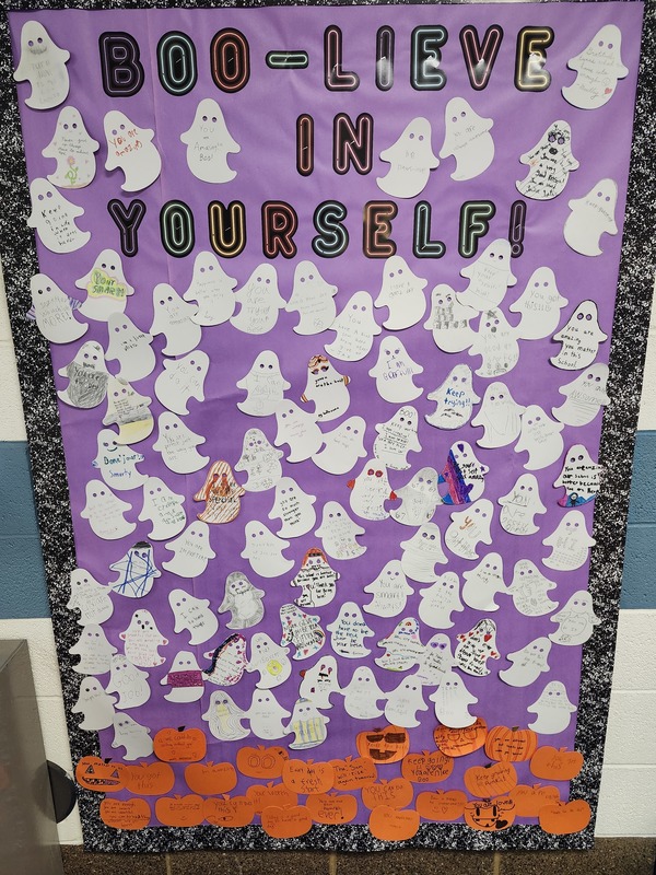 Board full of ghosts with positive words of affirmation written on them.