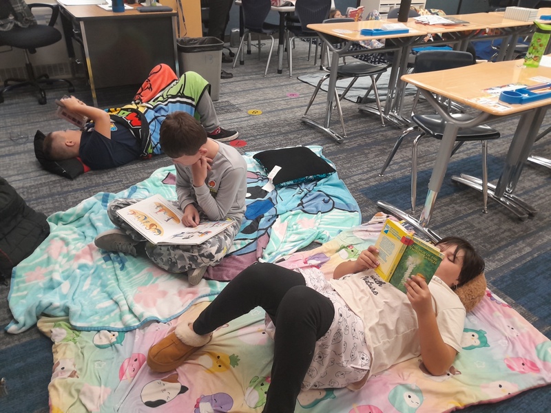 Student laying on blankets in their classroom reading