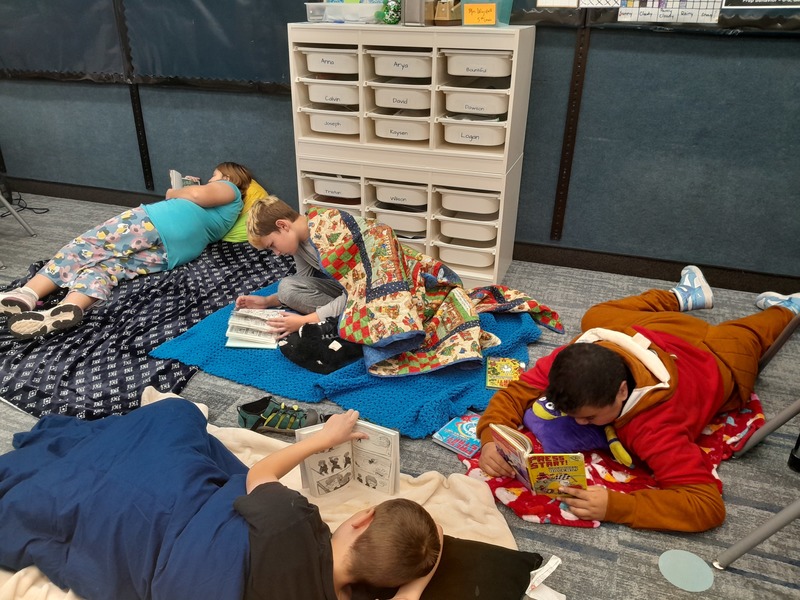 Students laying on blankets in their classroom reading