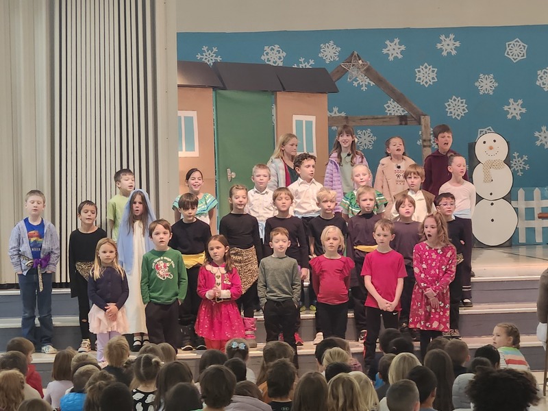 Students lined up on the stage steps singing in the play.