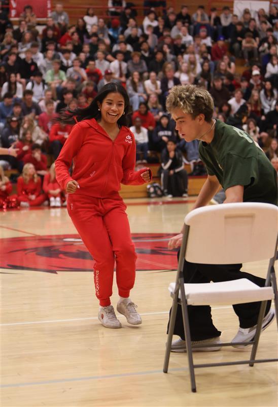 Female student wearing red and running to a chair