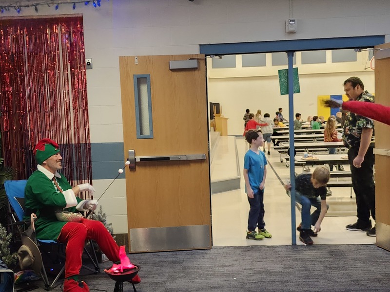 Pinky the Elf in front of the lunchroom throwing marshmellows at staff