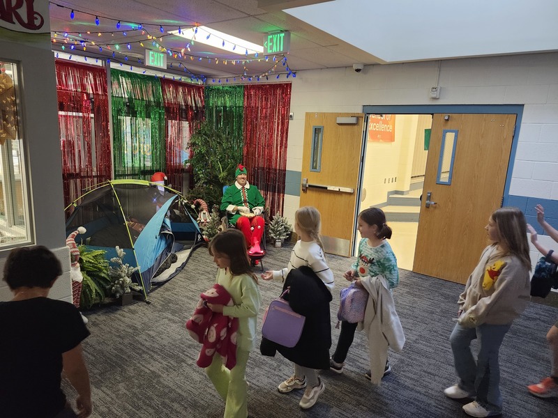 Pinky the Elf in front of a decorated hallway throwing marshmellows at students.