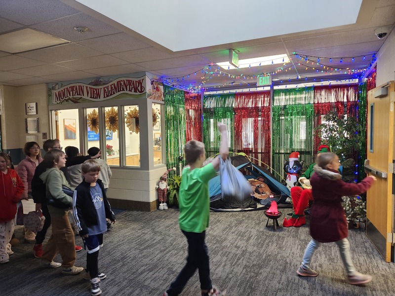 Pinky the Elf in front of a decorated hallway throwing marshmellows at students.