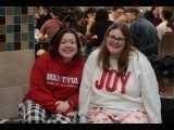 Two female students sitting and smiling in pajamas