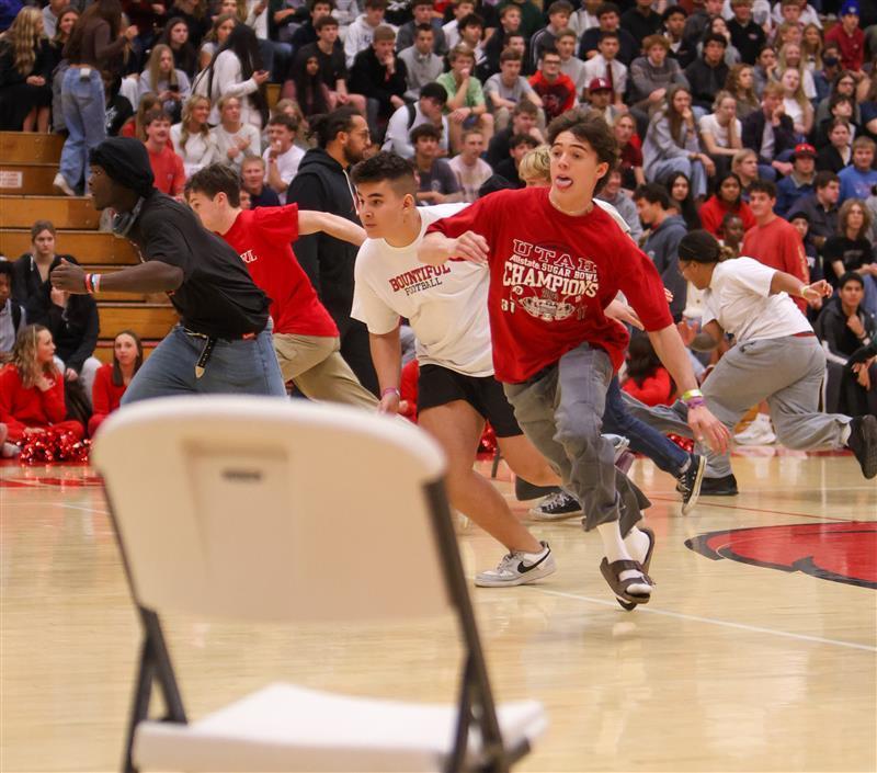 student wearing red and running to a chair