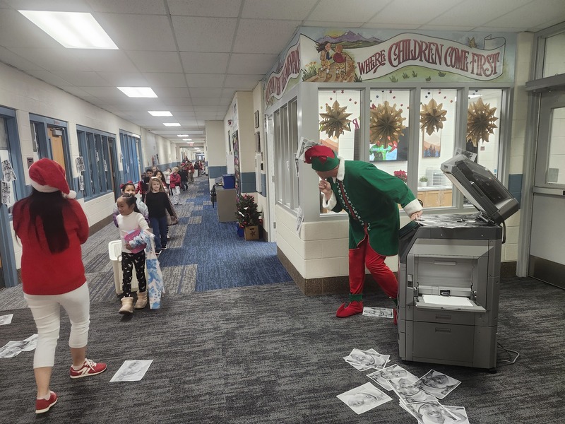 Pinky the Elf next to the copier with a 1st grade class walking by