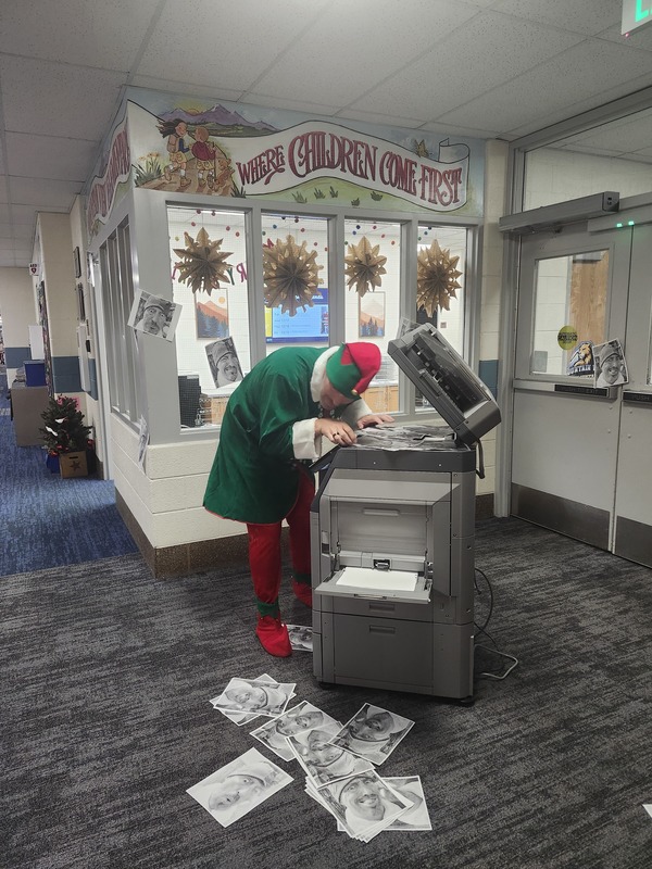 Pinky the Elf with his head in the copy machine making copies