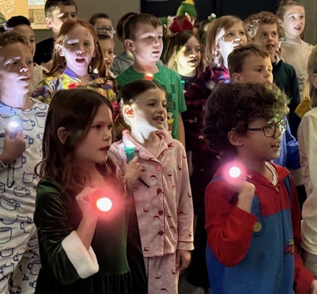 Students holding flashlights and singing