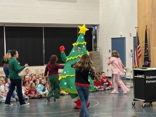 Faculty members dancing around a Christmas tree.