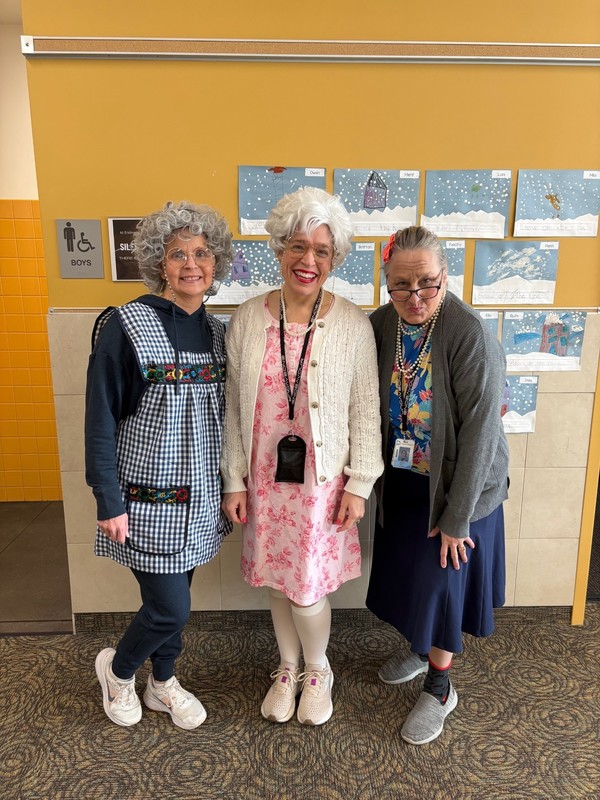 Teachers dressed as 100 year olds posed infront of a classroom