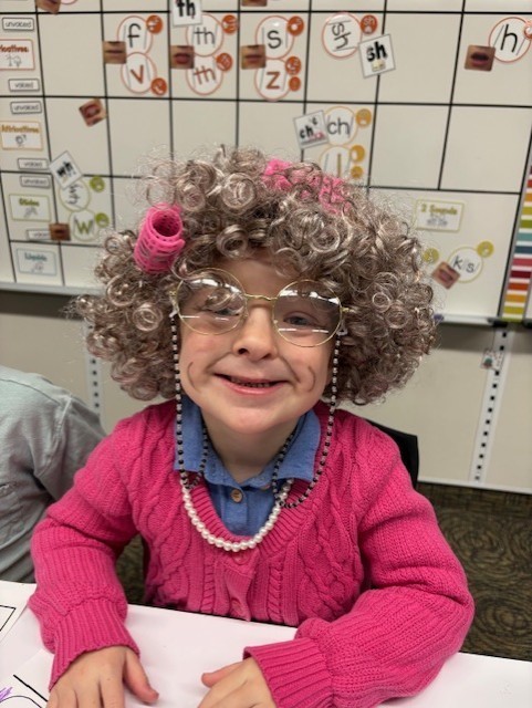 Student dressed as 100 year old at a desk in a classroom