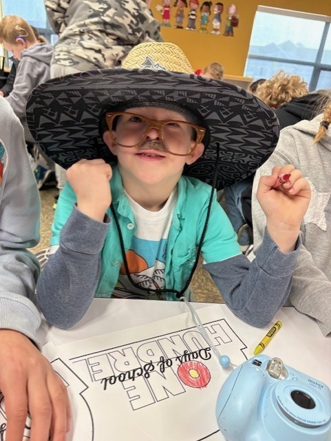 Student dressed as 100 year old with a hat on in a classroom