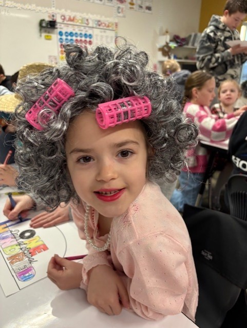 Student dressed as 100 yeard old with curlers in her hair in a classroom