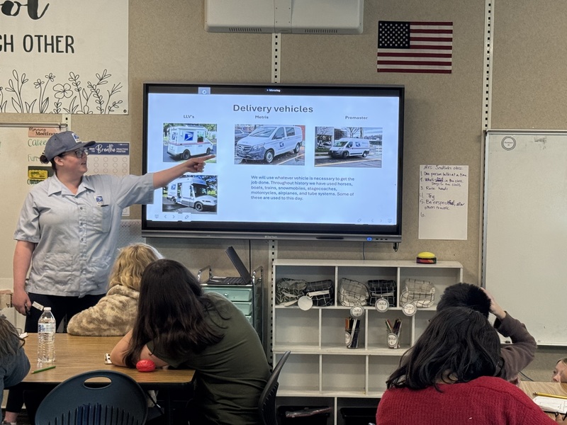 Post office worker showing students the different trucks they drive.