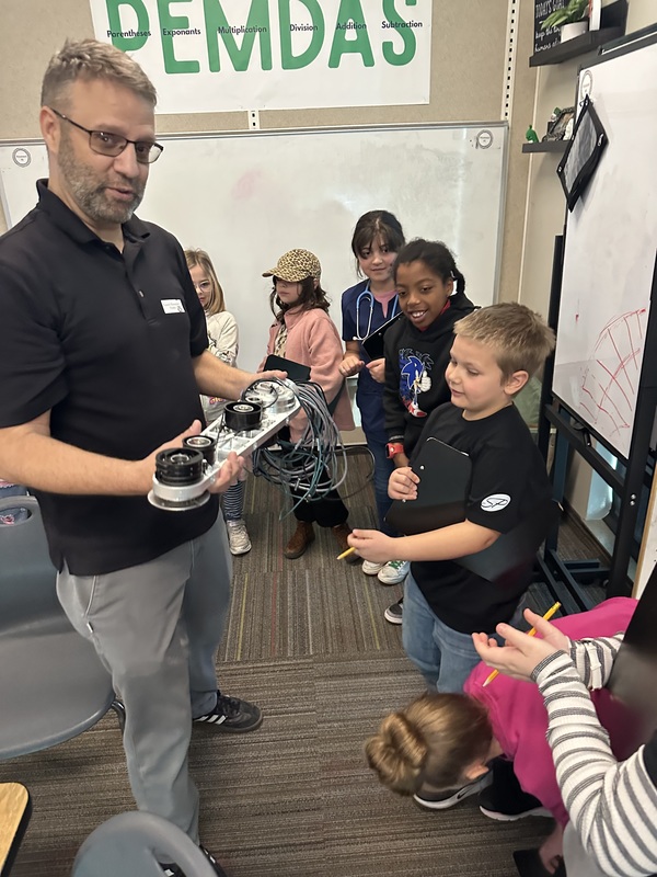 Medical engineer showing students a robot part.