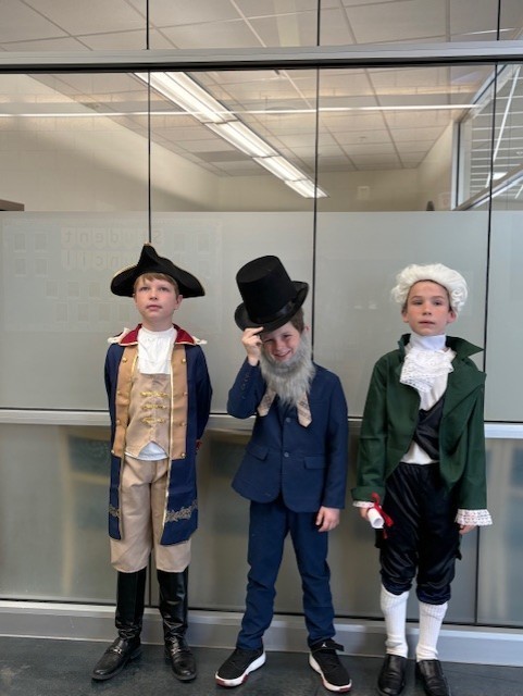 Students dressed in character as historical figures with hats and wigs