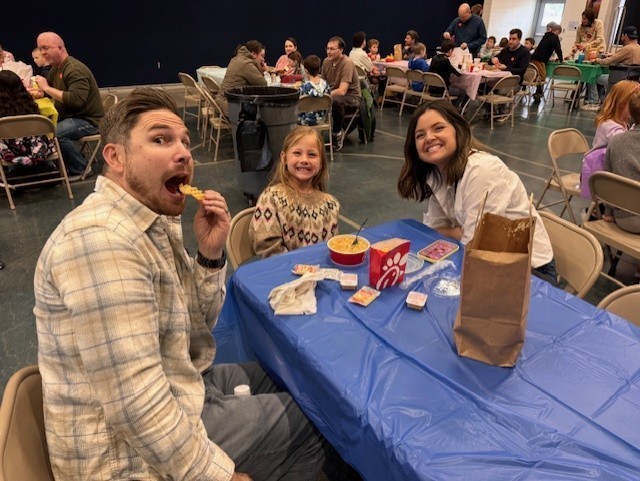Students eating lunch with their family with a blue tablecloth