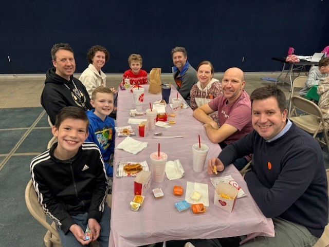 Students eating lunch with their families on a pink tablecloth