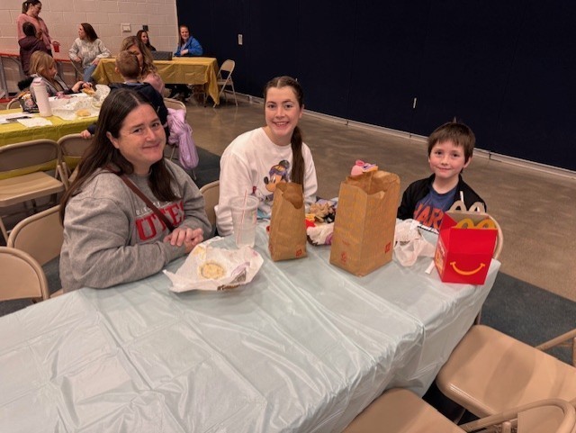 Student with their family eating lunch on a white tablecloth