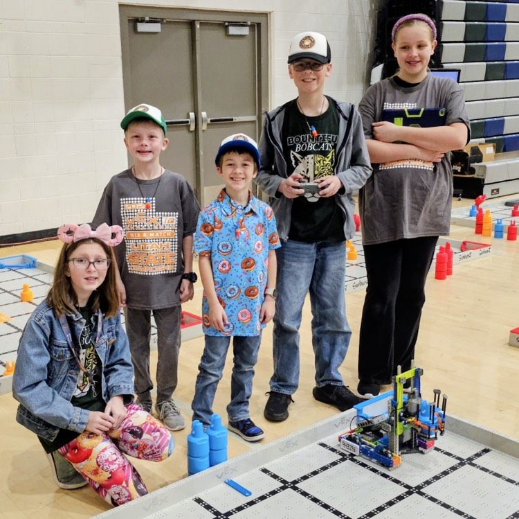 Five Bountiful elementary students from the VEXers robotics team pose beside their VEX IQ robot and competition field at the Utah State Championship.