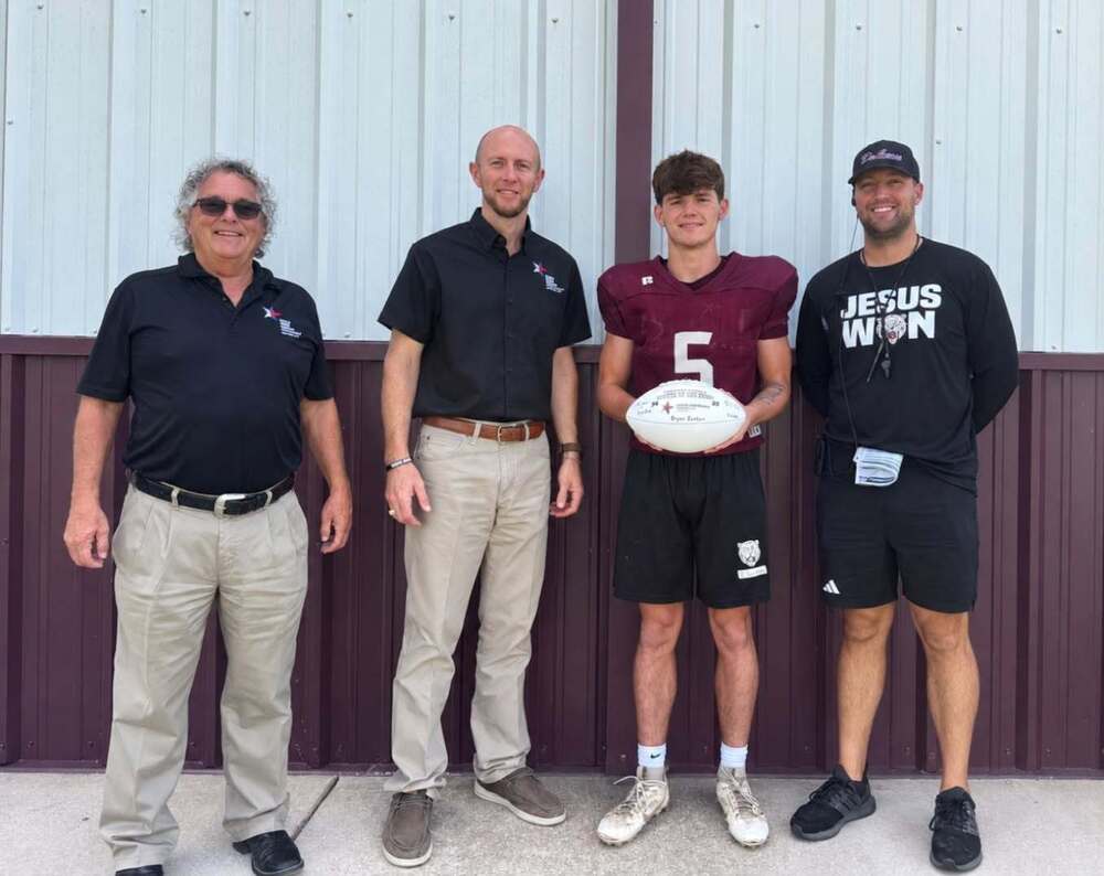two men standing with football player and coach