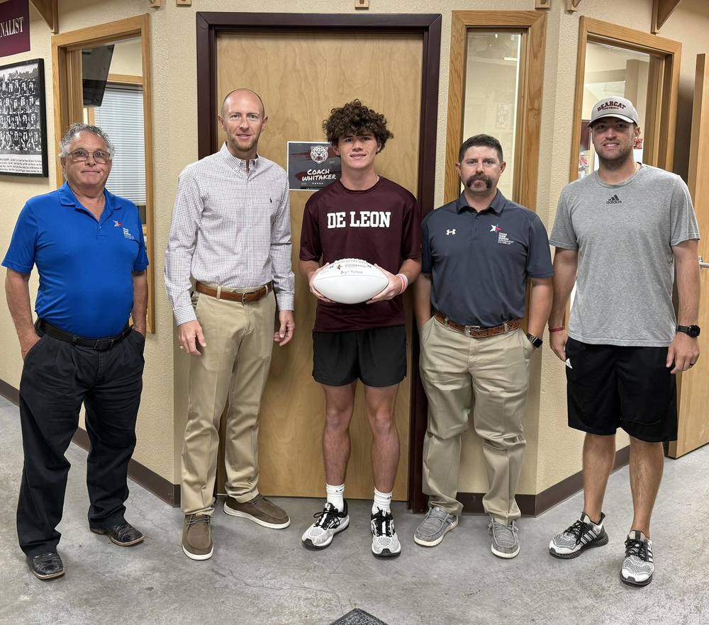 3 reps from comanche county farm bureau posing with football player and head coach