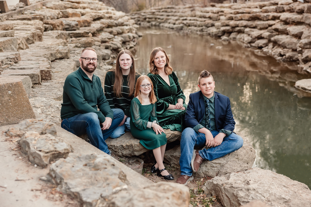dr taylor delka and family group picture sitting on rocks along side river