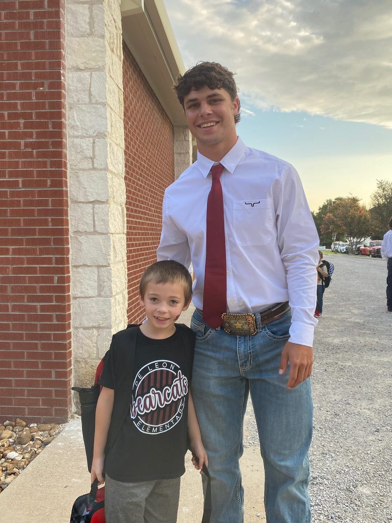 football player posing next to elementary student in black shirt