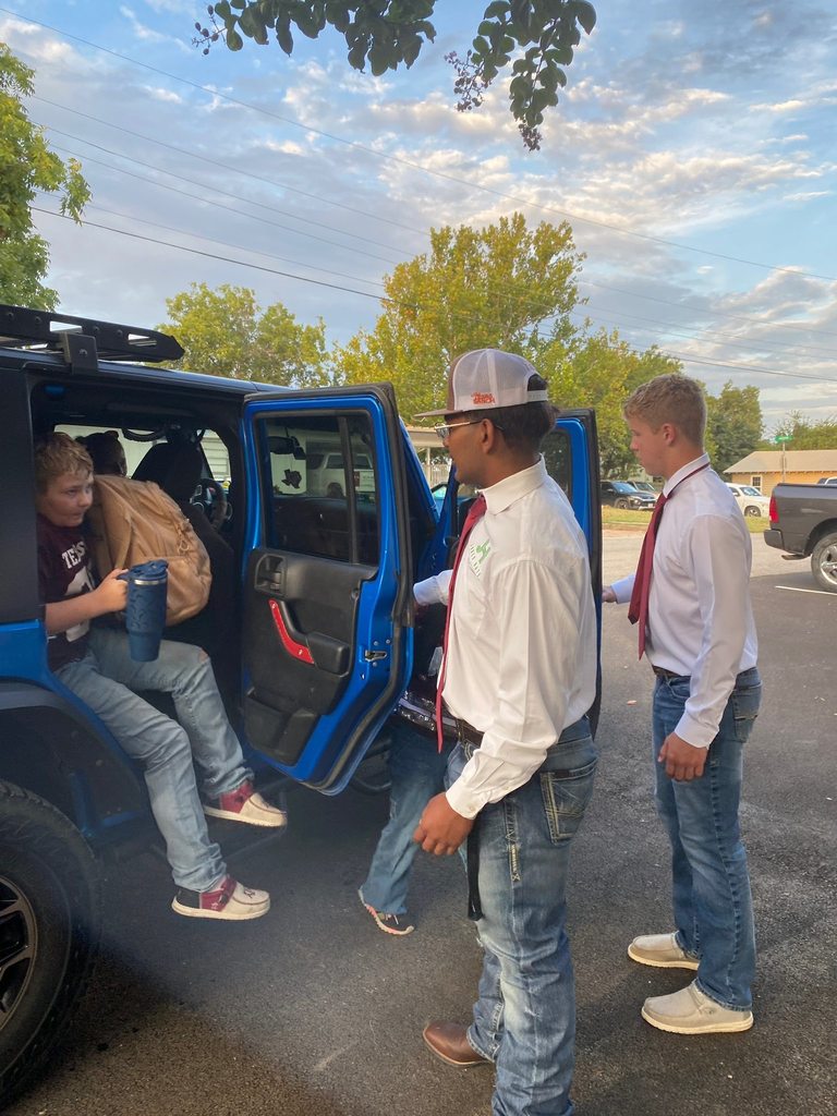 two football players opening doors to blue jeep for elementary students
