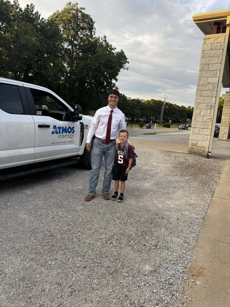 football player posing with boy next to white truck