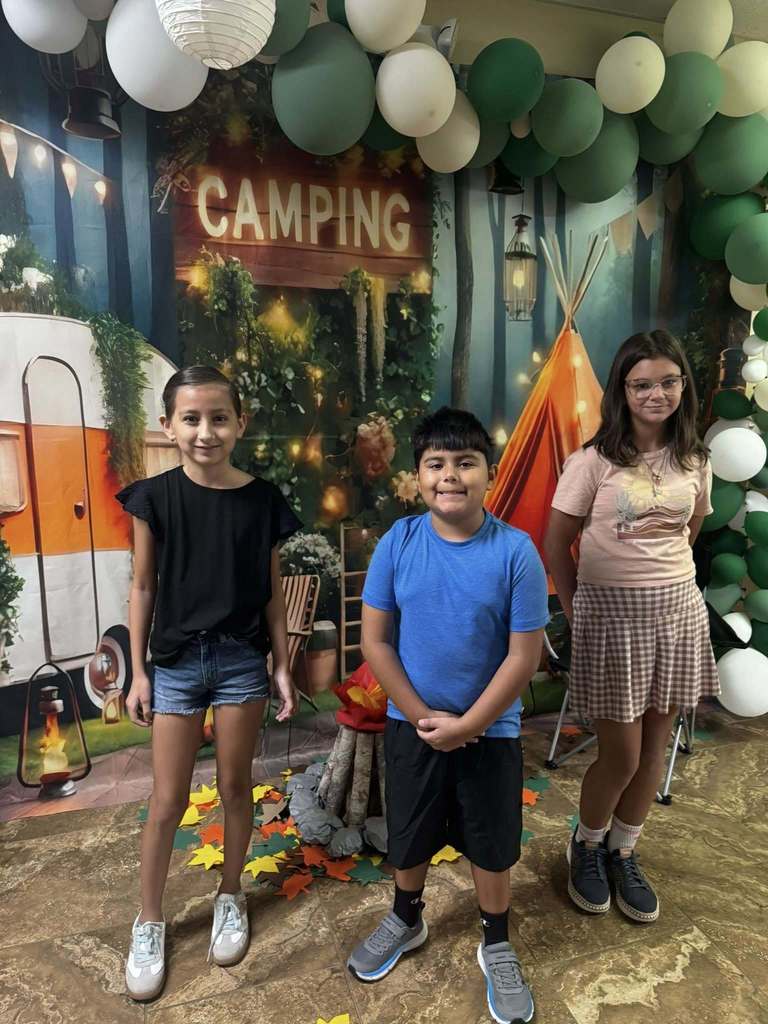 three students standing in front of campfire backdrop