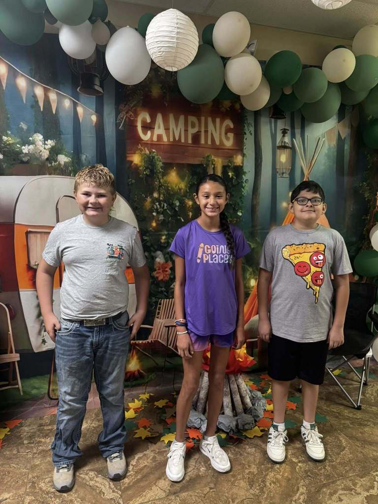 three students standing in front of campfire backdrop