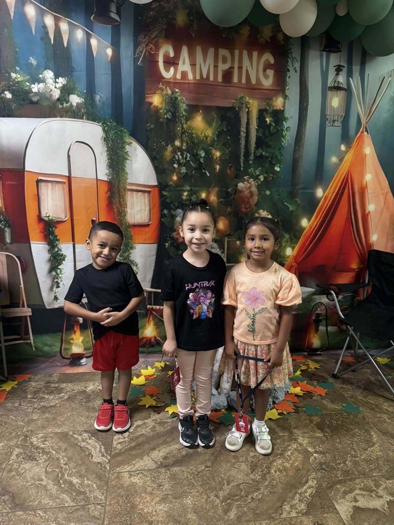three students standing in front of campfire backdrop