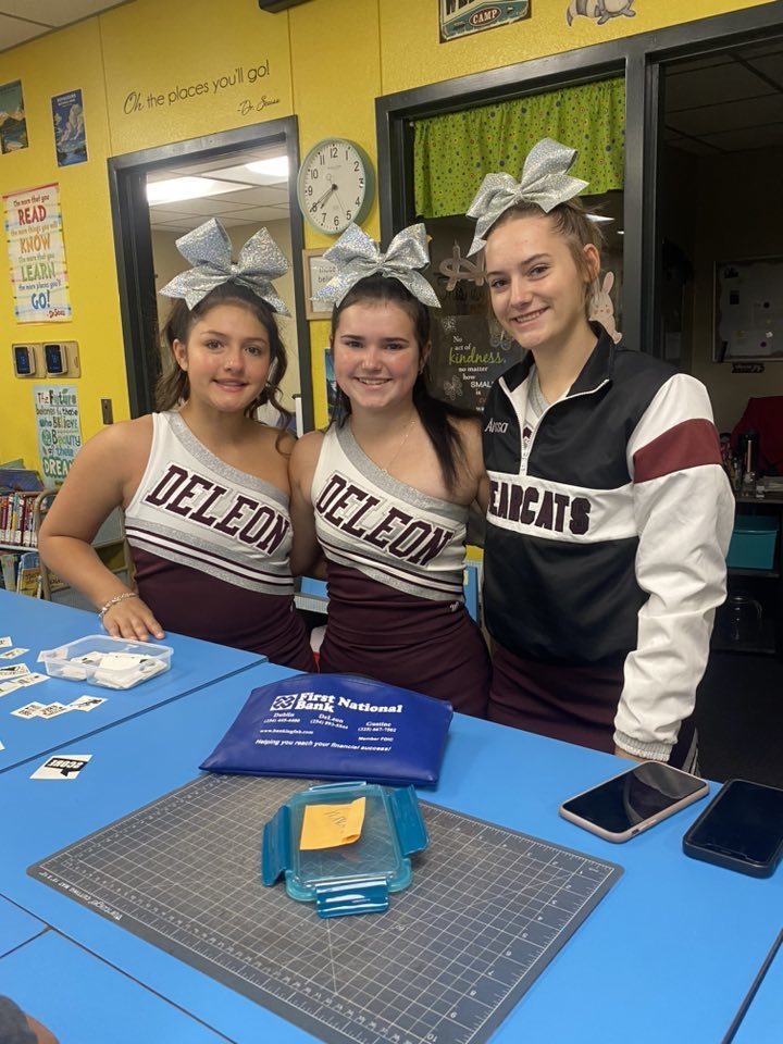 three cheerleaders standing behind counter in library