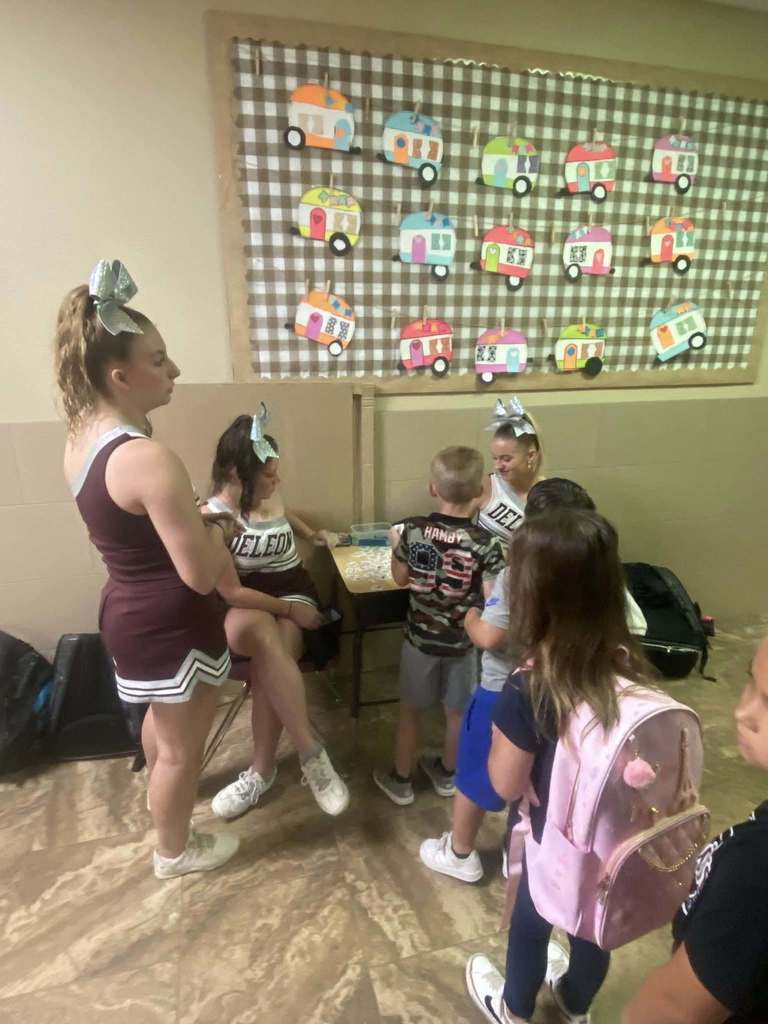 three cheerleaders selling tatoos to students in hallway