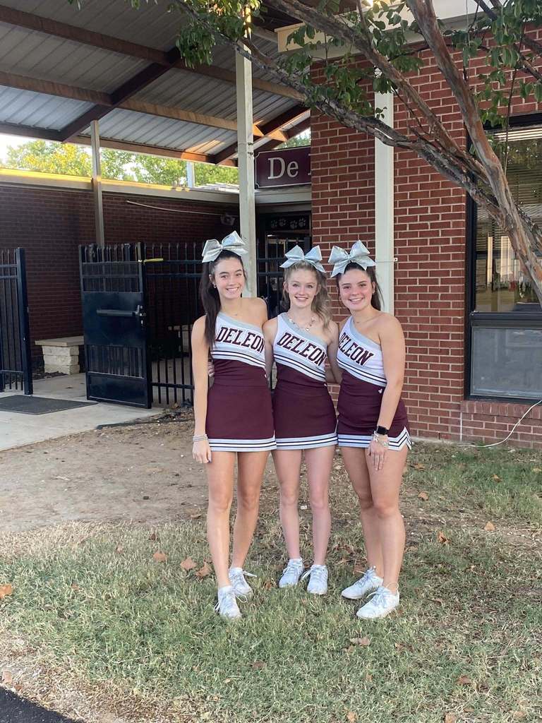 three cheerleaders outside school building