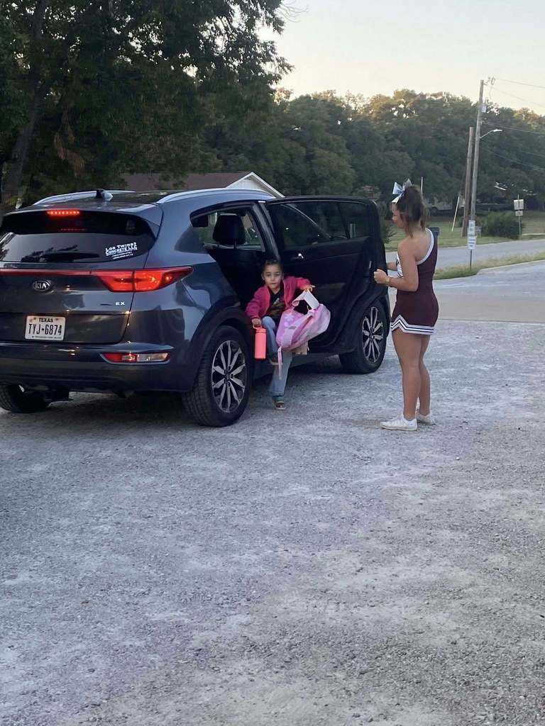 cheerleader opening car door for student