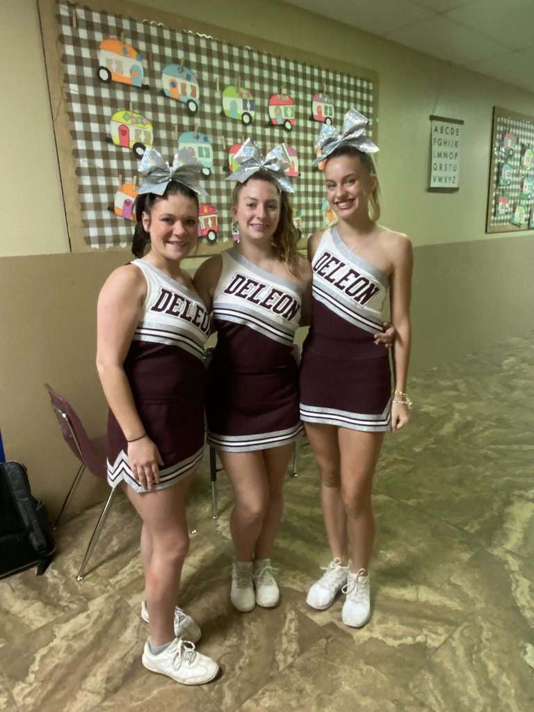three cheerleaders standing in hallway