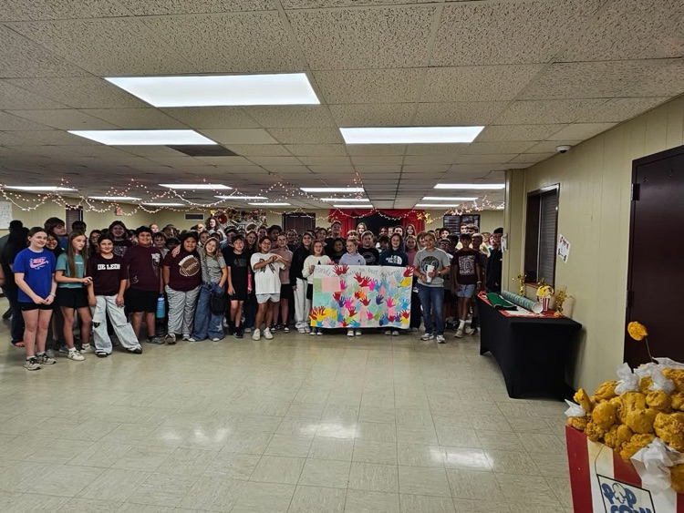 large group of students holding a big sign next to custodian