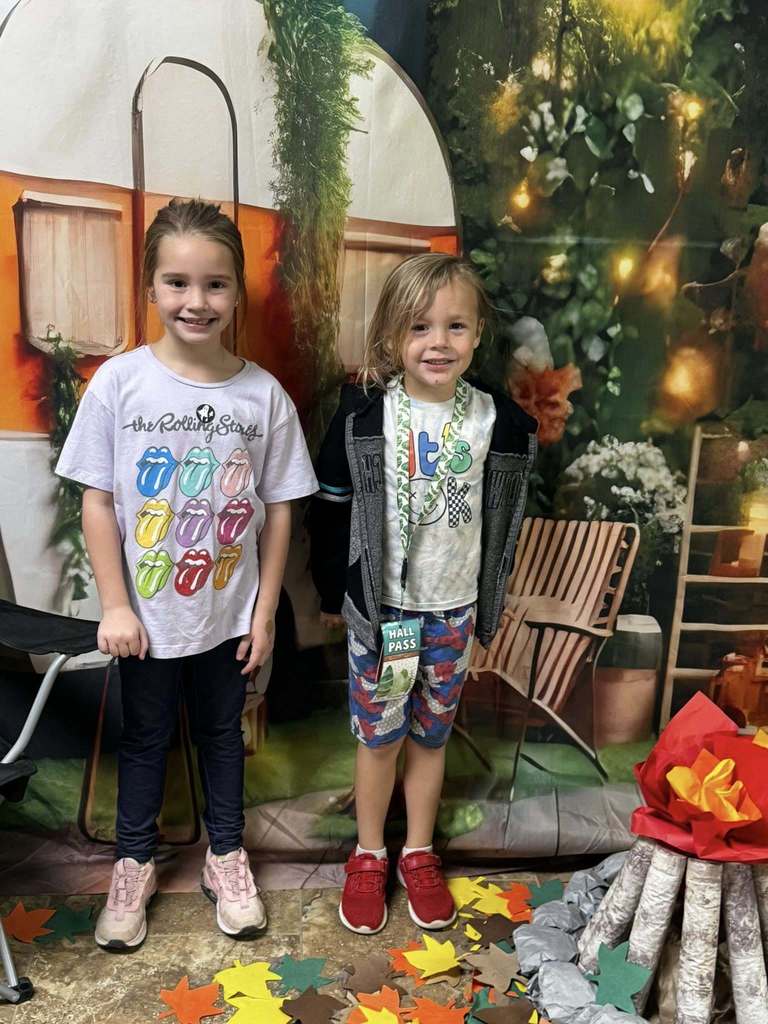 two campers of the week standing in front of campfire backdrop