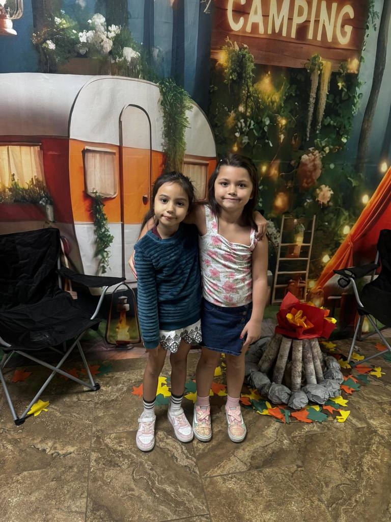 two campers of the week standing in front of campfire backdrop