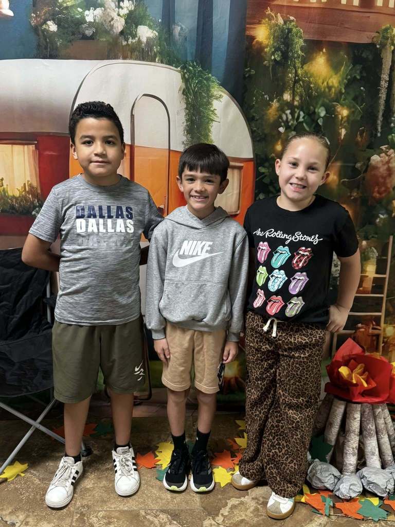 three campers of the week standing in front of campfire backdrop